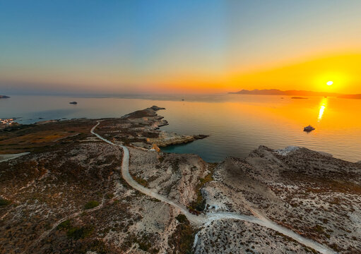 Sunrise over Mandrakia on Milos Island, Greece, illuminating the volcanic coastline and calm Aegean Sea with warm golden light, vibrant colors, and a peaceful Mediterranean atmosphere.