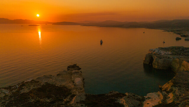 Sunrise over Mandrakia near Sarakiniko Beach on Milos Island, Greece. A volcanic coastline and calm Aegean Sea with warm golden light, vibrant colors, and a peaceful Mediterranean atmosphere.