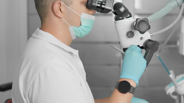 Closeup of a dentist wearing a face mask and blue gloves, utilizing a dental microscope during a patient procedure. Modern dental clinic environment emphasizes hygiene and advanced oral healthcare