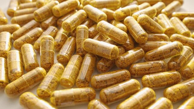 A detailed macro photograph showcases a large quantity of yellow powder capsules, highlighting their texture and clarity. This image reflects current health, nutrition, and supplement industry trends