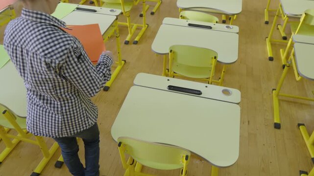 A girl in a checkered shirt prepares study materials in a sunlit classroom with contemporary furniture. The scene highlights back to school, learning, and academic preparation
