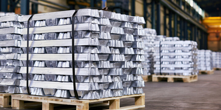Metal production. Stacked aluminum ingots secured on pallets await warehouse storage, industrial processing, export logistics and manufacturing supply operations.