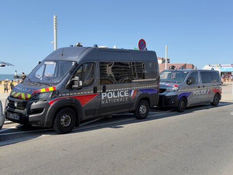 French national police vehicles at Calais beach conducting high-visibility patrols for public safety. 