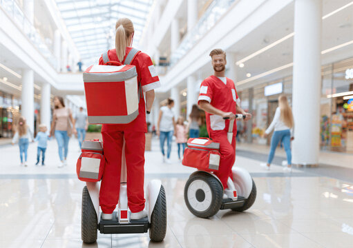 Emergency medical services. Paramedics patrol a busy shopping mall on Segways, providing rapid first aid response and mobile emergency medical support for visitors.