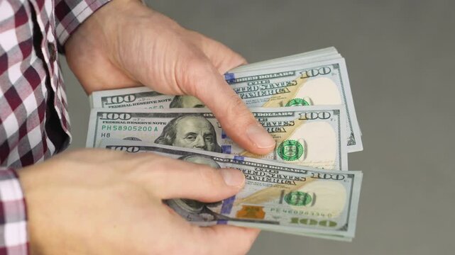 A person counts a stack of hundred dollar bills, highlighting themes of money management and financial planning. The image conveys concepts of investment, savings, and personal finance