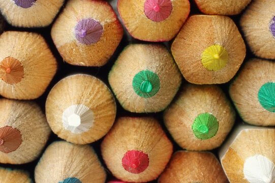 Macro close up of colorful pencil tips creating continuous background. Camera slowly zooms out from the sharp pencil points revealing a large vibrant composition of colored pencils