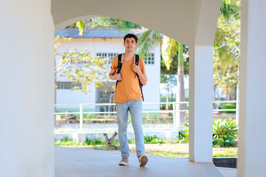Young university student walking across campus with a backpack. Concept of higher education, academic life, learning, confidence, and student routine.