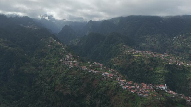 Dramatic aerial of S&atilde;o Roque do Faial village beneath Madeira's cloud-covered mountains