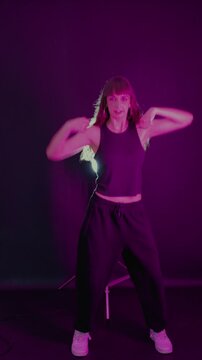 Young energetic woman dancing in neon light