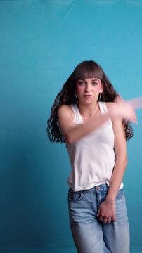 Energetic young woman dancing to music against a blue background