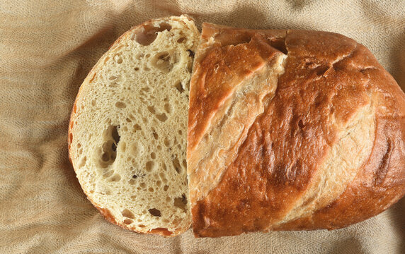 Bread still life. A fresh baked loaf of bread with a slice of bread on kitchen towel.