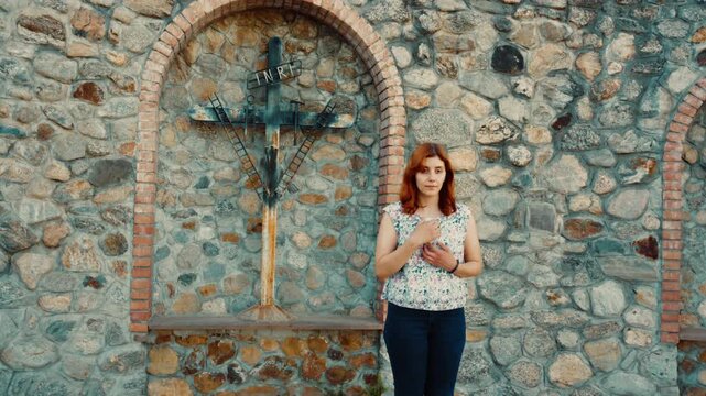 Woman prays next to the crucifix at Calvary in Italy for her Christian religion