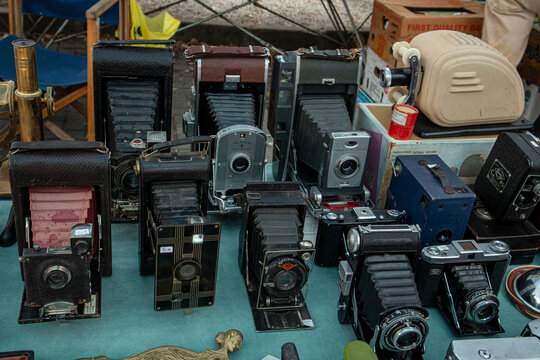 XALO, SPAIN - JUNE 20, 2026.Collection of rare vintage folding bellows cameras and film equipment at an antique flea market display