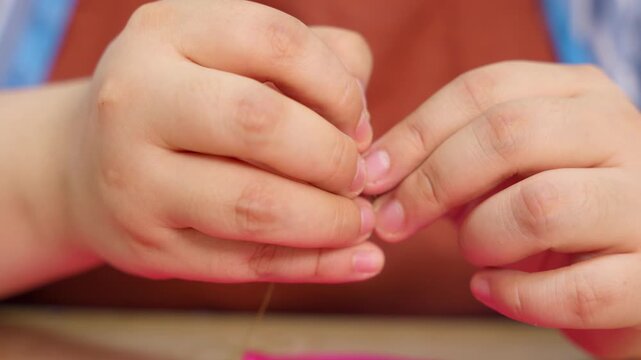 Person's hands carefully threading needle in slow motion