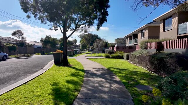 Walking perspective on a footpath in a quiet suburban neighborhood in &nbsp;Seaholme, Melbourne, Australia. A green nature strip,&nbsp;residential homes line the&nbsp;pedestrian&nbsp;sidewalk