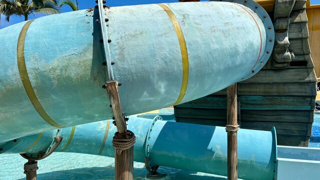 Closeup of a blue enclosed water slide at an outdoor water park on a sunny summer day featuring tubular aquatic playground equipment