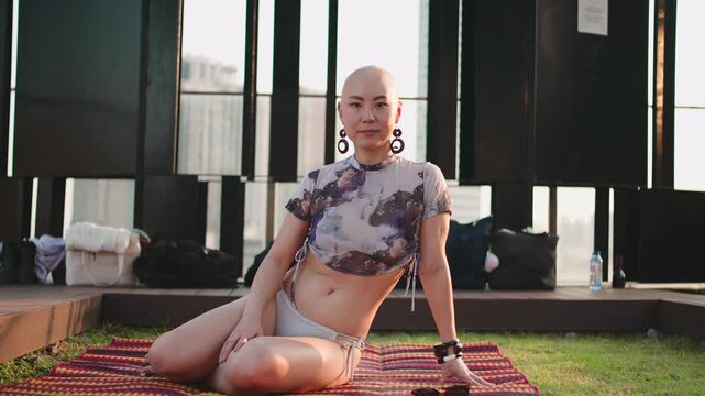 Confident bald woman posing and smiling on a rooftop at sunset