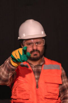 Construction worker in safety helmet touching invisible virtual screen isolated on black background