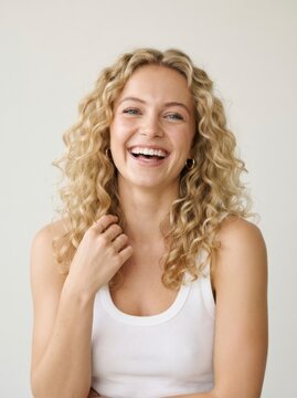 Happy young woman with curly blonde hair. Smiling girl portrait on white background.