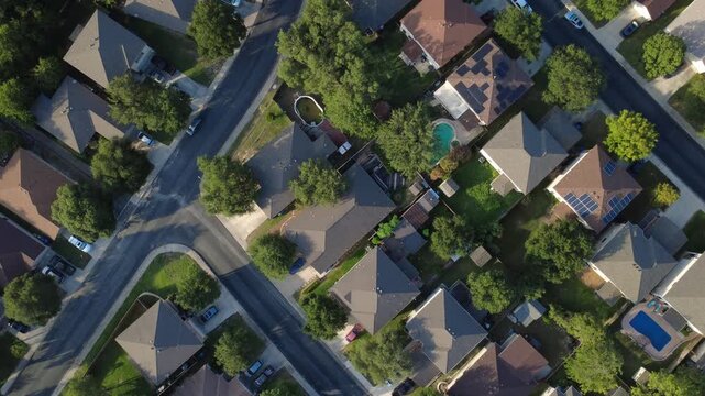 Suburban street intersections cross master planned community single family suburban houses near Culebra Road. Angular rooflines frame fenced yards and parked vehicles, San Antonio, Texas