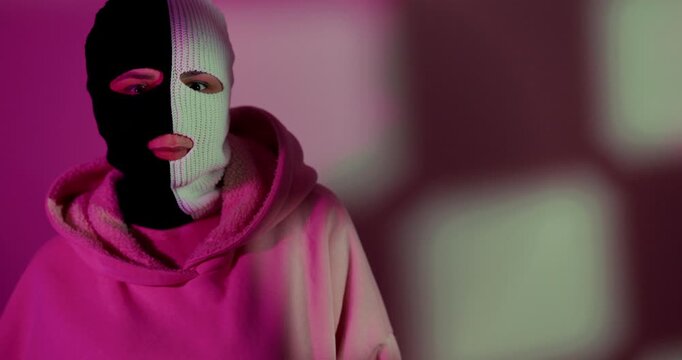 Woman wearing split black and white balaclava. Mysterious female character in mask representing duality and anonymity. Concept of hidden identity and subculture fashion.