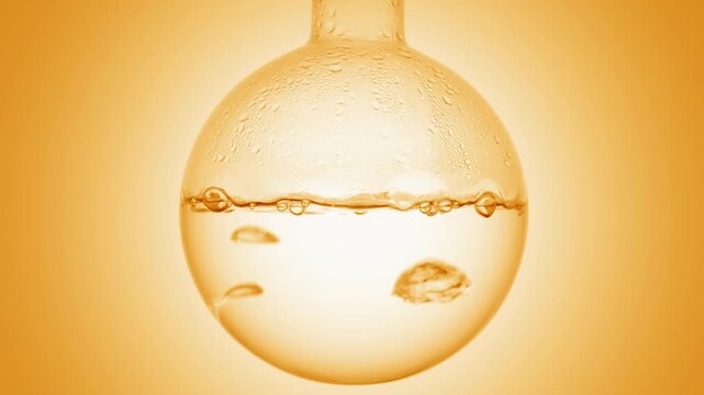 Close-up of bubbles developing and traveling upward through clear transparent liquid boiling in a round-bottom flask condensing on it's walls on orange ramp background