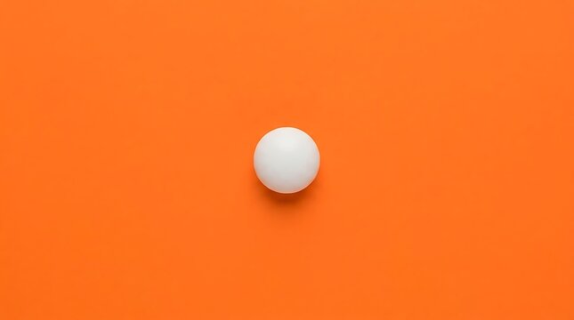 Single white ping pong ball on orange background, minimalist top view.