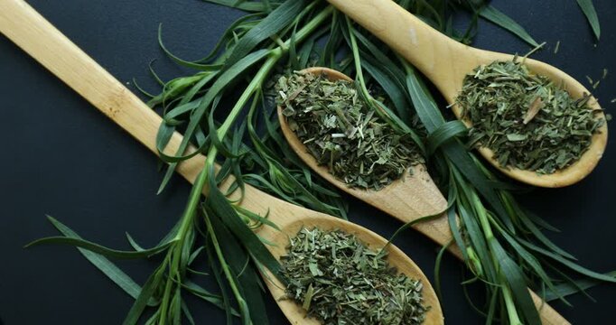 Dried and fresh tarragon on black surface, top view