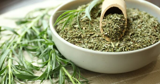 Dried and fresh tarragon in bowl on table, closeup