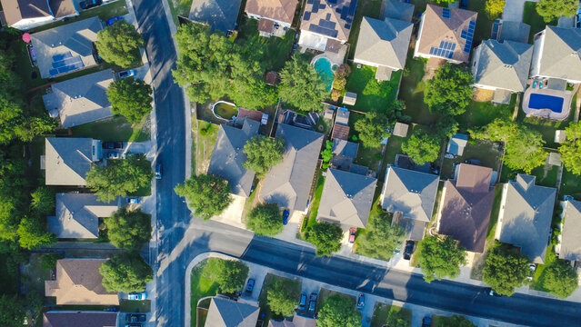 Magnolia Park Drive master planned community single family suburban houses border Slickrock Creek channels. Solar panels cap pitched roofs of dense housing beside oak trees, San Antonio, Texas