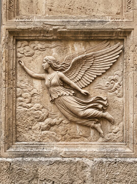 stone relief featuring a classical-style winged angel surrounded by clouds