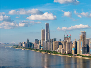 Fototapeta premium A scenic view of the modern city skyline featuring tall skyscrapers along the river in Wuhan China under a bright blue sky with white clouds