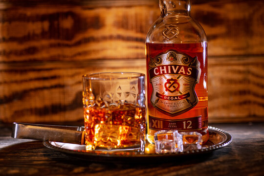 Chivas Regal 12 bottle and whisky tumbler sit on a reflective serving tray.