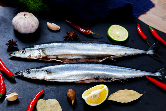 Raw saury fish surrounded by chili garlic lime star anise dark slate