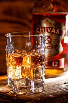 Whisky glass takes focus before a blurred Chivas Regal 12 bottle.