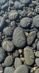 Obraz premium Smooth Wet Pebbles with Sunlight Ripples on Shallow Beach Shore