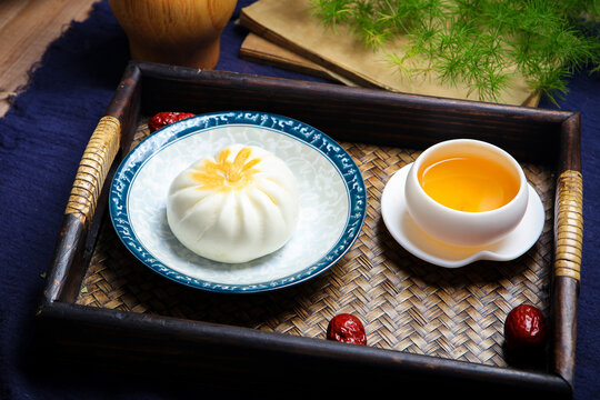 Three pan fried buns on blue and white porcelain plate tea chopsticks dark cloth
