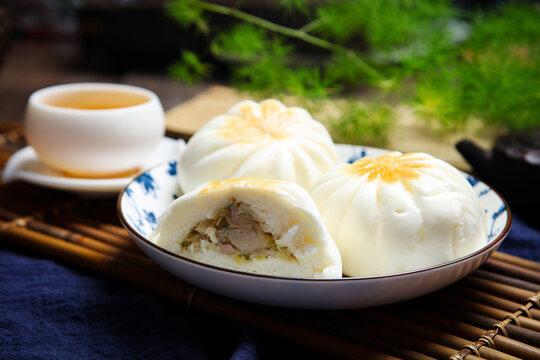Three pan fried buns on blue and white porcelain plate tea chopsticks dark cloth
