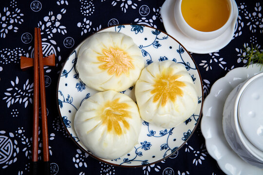 Three pan fried buns on blue and white porcelain plate tea chopsticks dark cloth