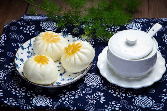 Three pan fried buns on blue and white porcelain plate tea chopsticks dark cloth
