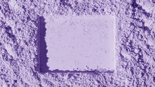 Top perspective vertical capture of a violet natural powder surface imprinted with a rectangular shape moving directional light casts fluid and shifting shadows