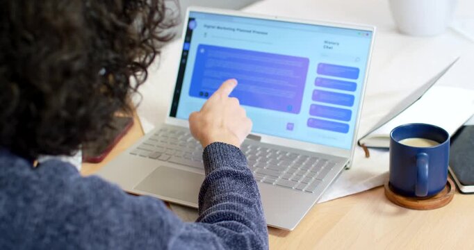 African American male tapping laptop chat scrolling reaching blue mug sipping at desk while working