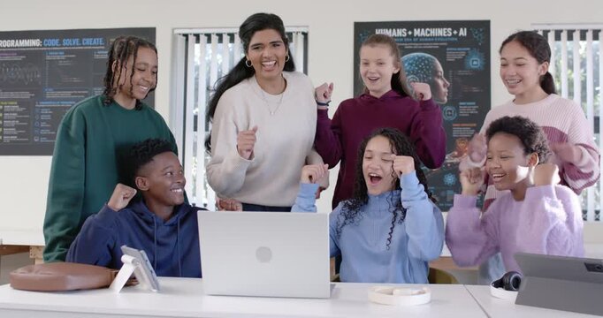 Diverse students with female mentor in STEM lab reacting to laptop showing code output and cheering