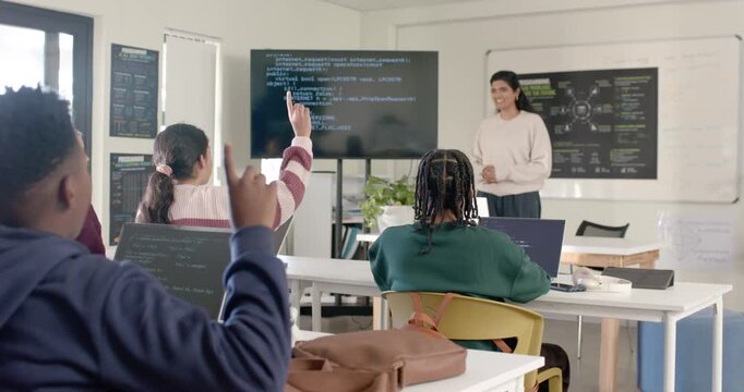 Teenage hoodie student raising hand asking as teacher showing code on screen, laptop, copy space