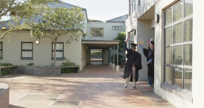 Diverse grads exiting right door running into courtyard waving diplomas celebrating in caps, gowns