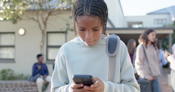 Youth female African holding phone at chest, tapping, swiping, focusing with padded strap on campus