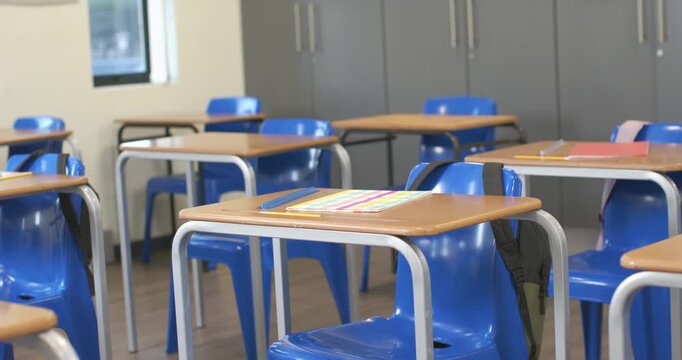 Shot start, camera is shifting, angling to frame front row desk, showing classroom ready for lesson