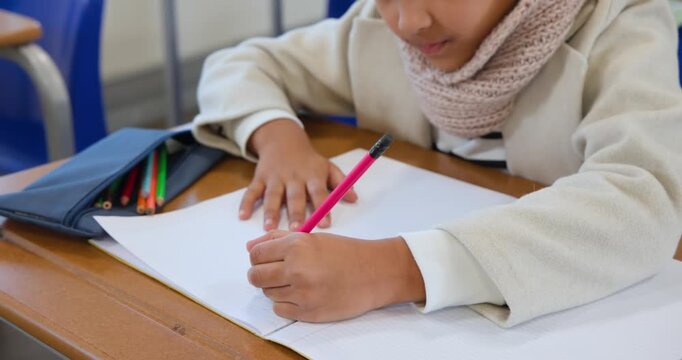 African American child balancing pink pencil opening case choosing green, drawing in pad at desk