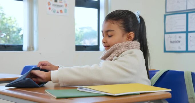 African American girl at desk reaching for pencil case, sorting pens, stacking books, resting chin