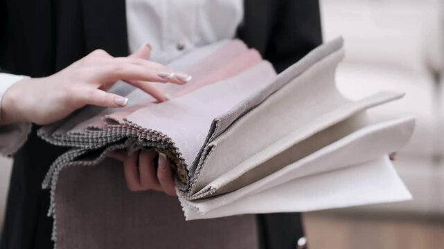 Close up of an interior designer reviewing fabric swatches and soft textile samples.